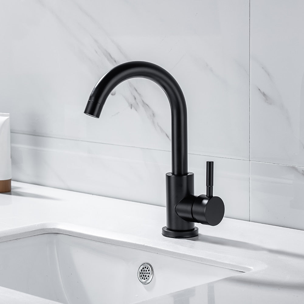 Black kitchen faucet on a white sink with a light gray tiled wall background