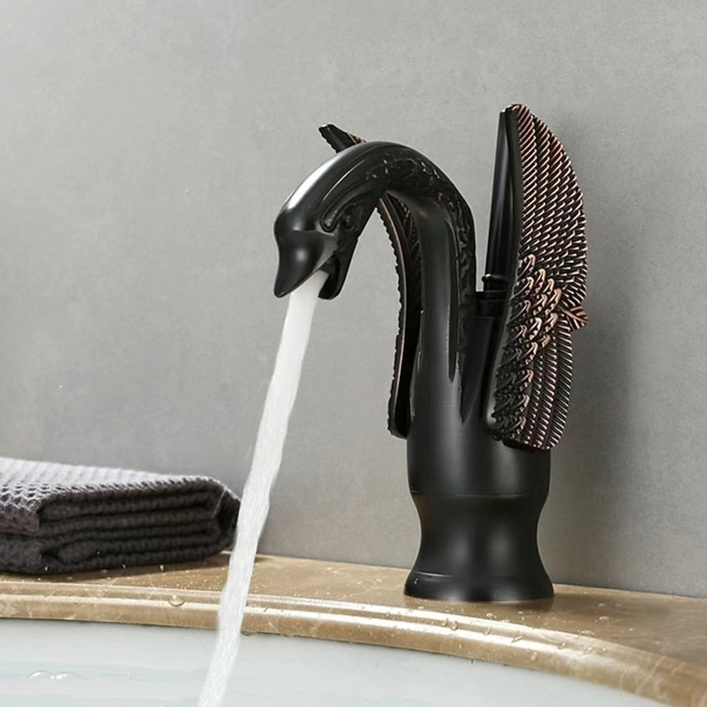 Black swan-shaped faucet with water flowing, sponge, and towel on a gray background